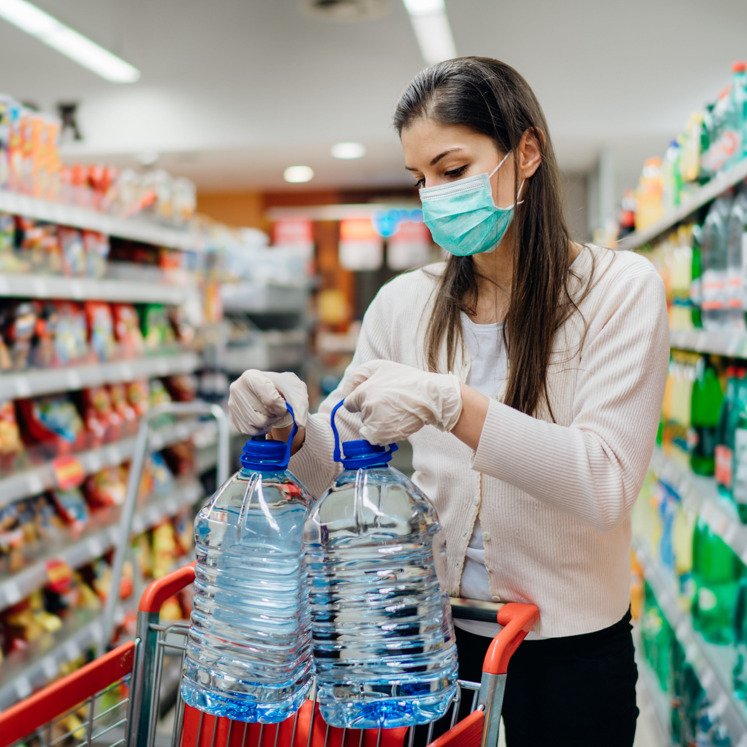 woman shopping for water while wearing gloves and a mask 