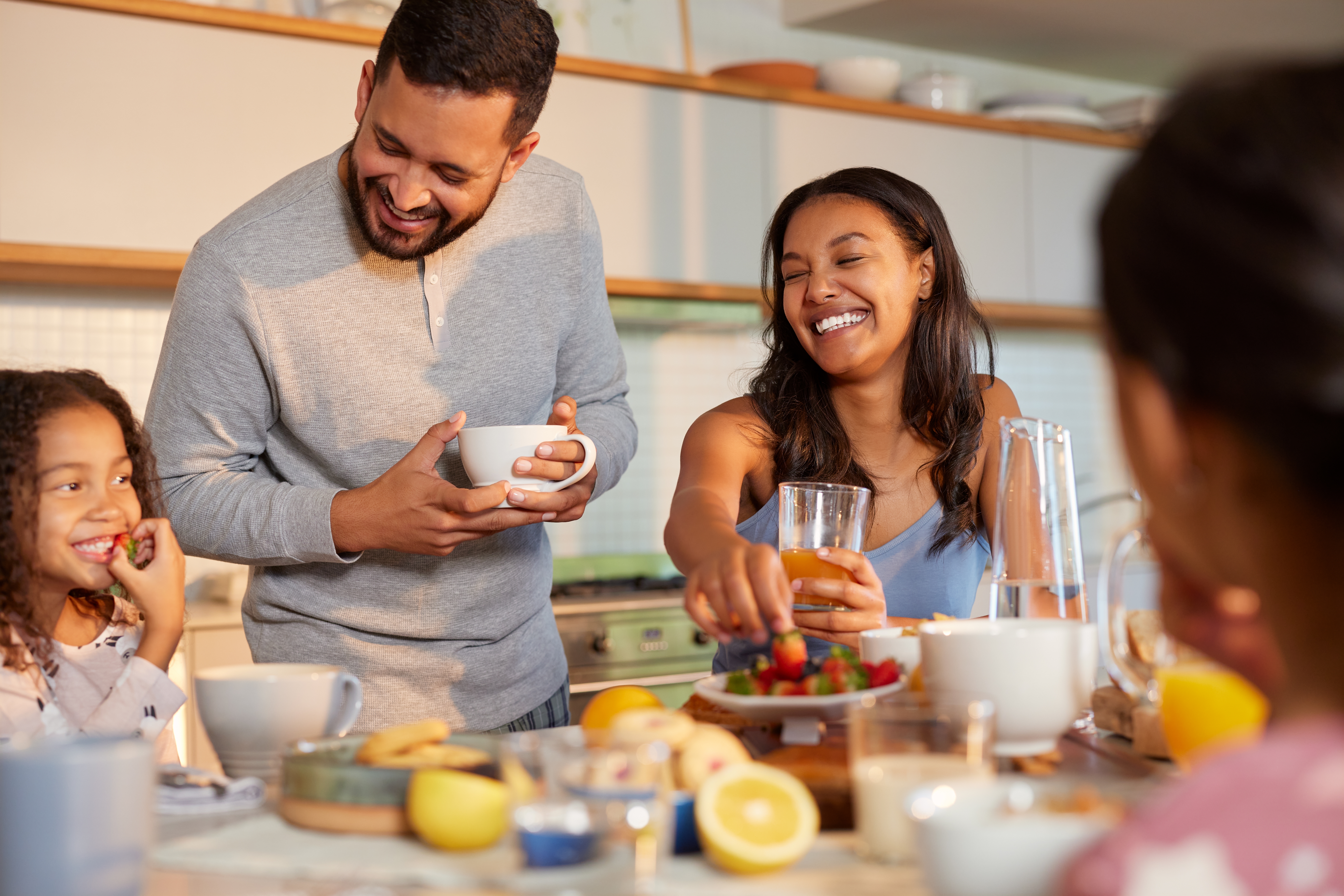 Family sitting around table smiling and picking from a bowl of strawberries